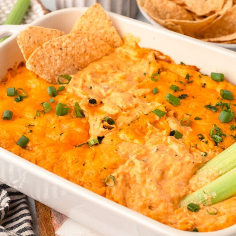 Frank’s Red Buffalo Chicken Dipwith melted cheese, green onions, and tortilla chips on a white serving dish.