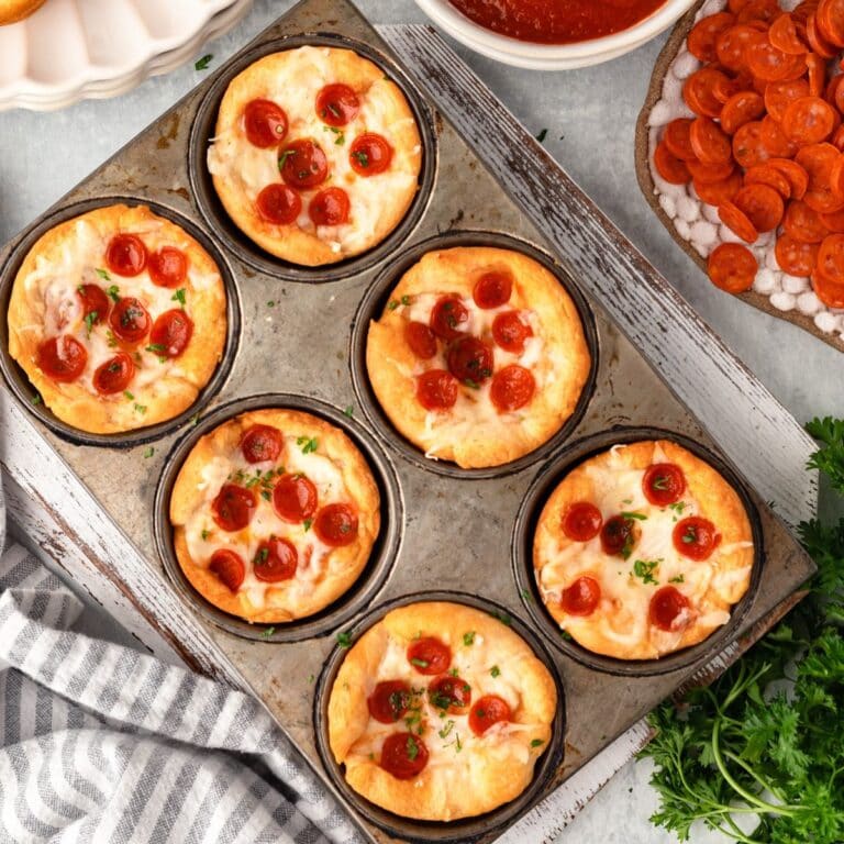 Mini California-style pizza cups topped with cherry tomatoes and fresh herbs.